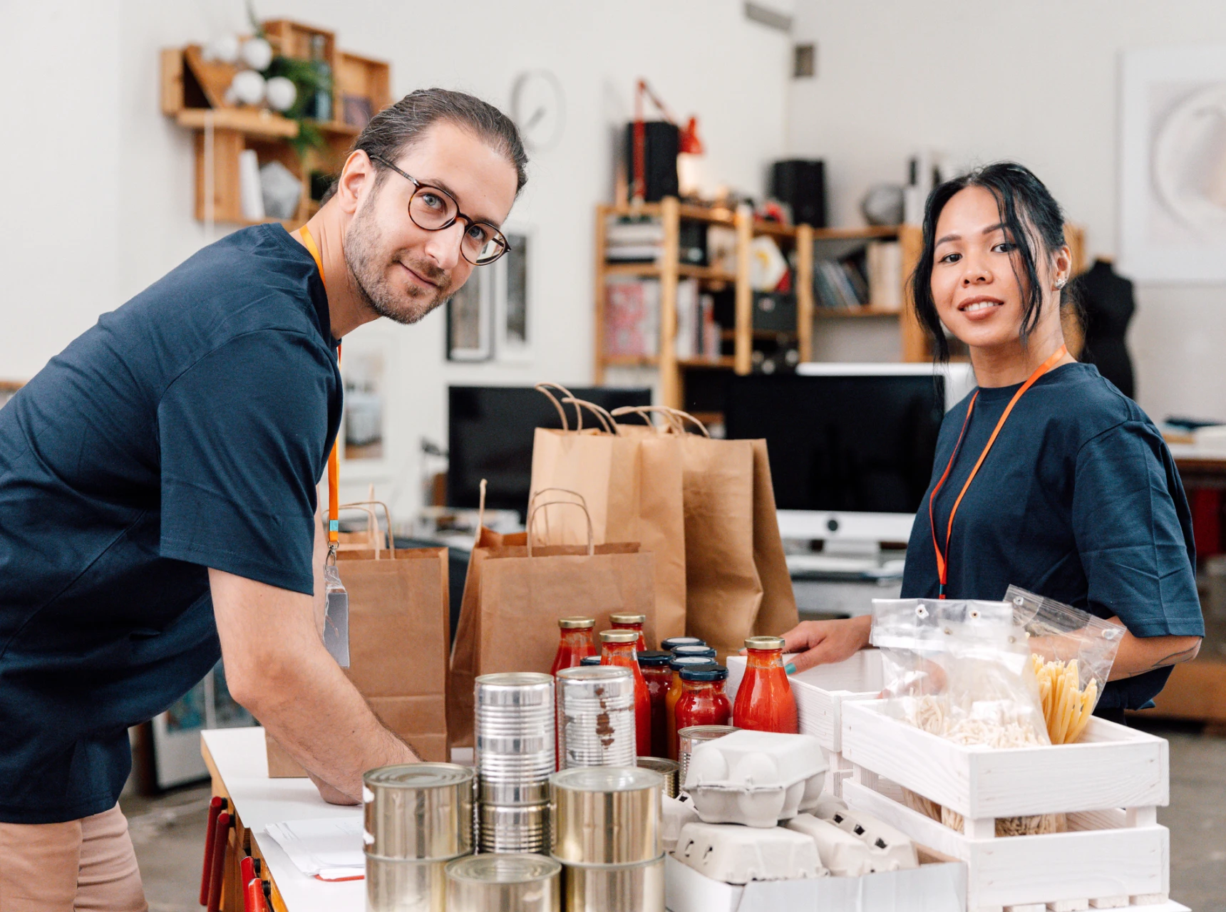 Two people organizing food donations in kitchen.