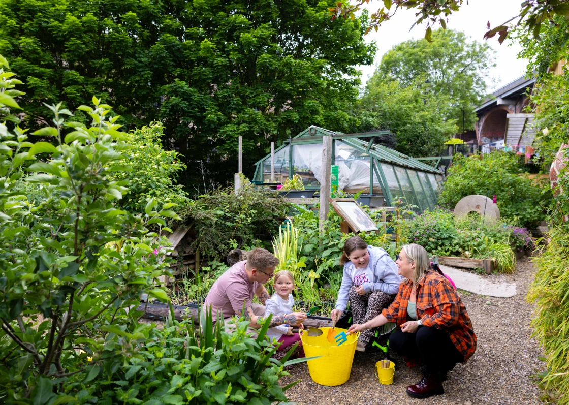 Family gardening together in lush backyard.
